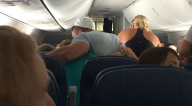 Tim Tebow prays with a family on a Delta flight.