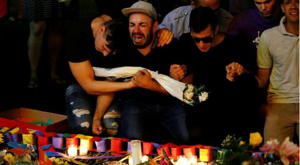 A man sits and cries after taking part in a candlelight memorial service the day after a mass shooting at the Pulse gay nightclub in Orlando, Florida.