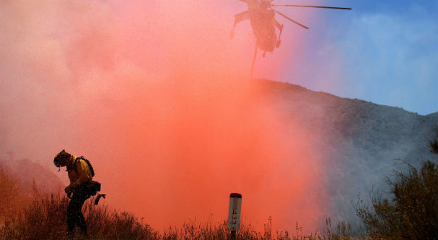 A fire fighter is sprayed with retardant as a helicopter makes a drop as emergency workers continue to battle the so-called Sand Fire in the Angeles National Forest near Los Angeles, California