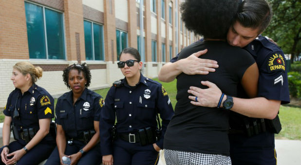 A supporter hugs a Dallas police officer at a makeshift memorial at police headquarters following the multiple police shootings in Dallas, Texas.