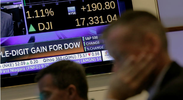 Traders work on the floor as a screen displays the Dow Jones Industrial average just after the opening bell at the New York Stock Exchange