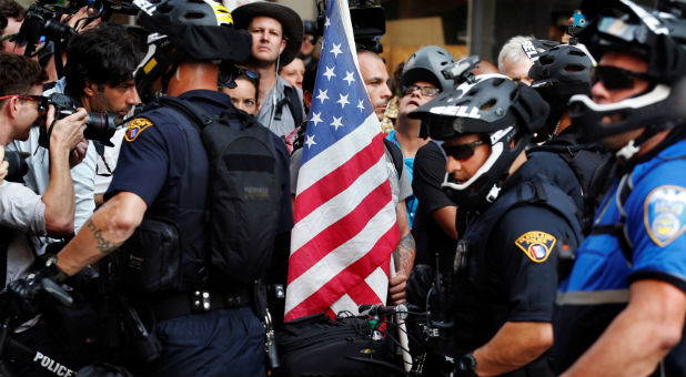 A protester with a U.S. flag confronts Cleveland Police police officers during a protest near the Republican National Convention in Cleveland, Ohio