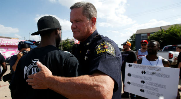 A Dallas police officer hugs a man following a prayer circle after a Black Lives Matter protest following the multiple police shootings in Dallas