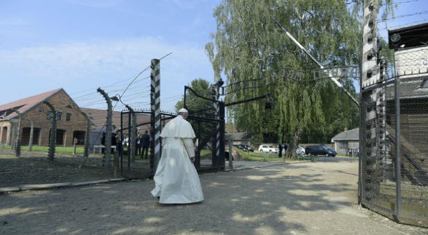 Pope Francis walks through a gate with the words
