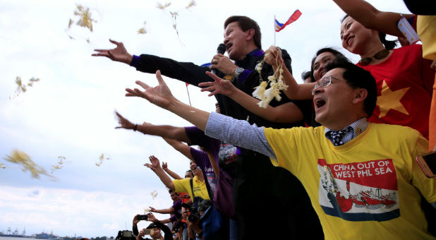 Protesters throws flowers while chanting anti-Chinese slogans during a rally by different activist groups over the South China Sea disputes