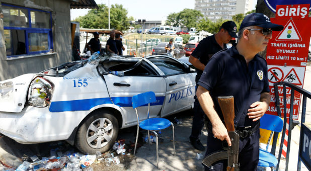 Police officers stand guard next to a damaged car at the entrance of the police headquarters in Ankara, Turkey.