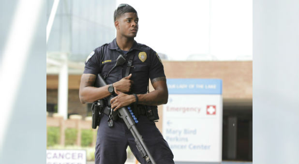 A police officer armed with a shotgun guards the entrance to Our Lady of the Lake Hospital after a fatal shooting of police officers in Baton Rouge, Louisiana.