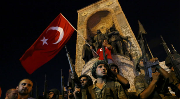 Turkish military stand guard near Taksim Square as people wave with Turkish flags in Istanbul, Turkey, July 16, 2016.