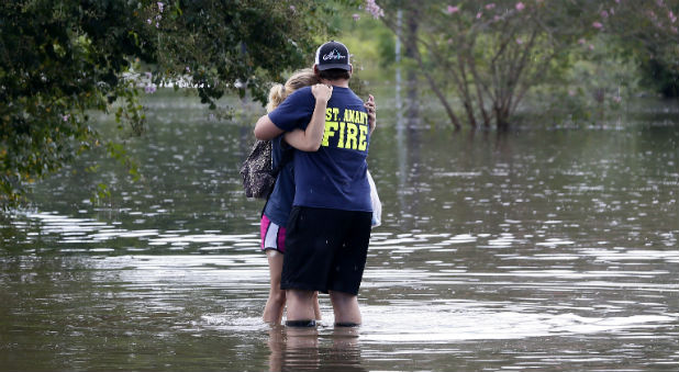 enton Affray, a firefighter with the St. Amant Fire Department, embraces his girlfriend Malie Geautrux on a flooded street in St. Amant, Louisiana