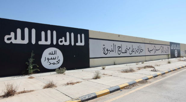 Islamic State painted flags and slogans are seen on a wall