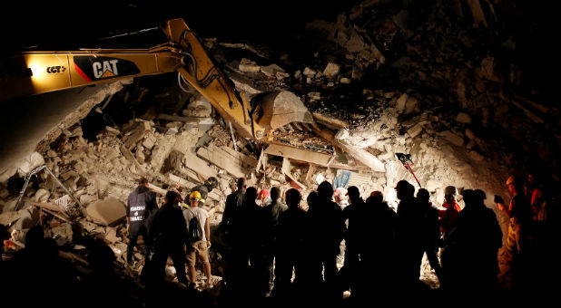 Rescuers work in the night at a collapsed house following an earthquake in Pescara del Tronto, central Italy