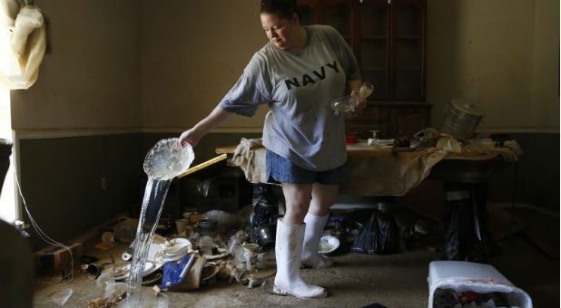 Marilyn Mays drains water from dishes in the dining room of her mother's home after heavy rains led to flooding in Denham Springs, Louisiana