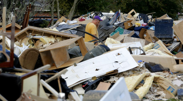 A man walks through piles of debris in front of flood damaged homes at the South Point subdivision in Denham Springs