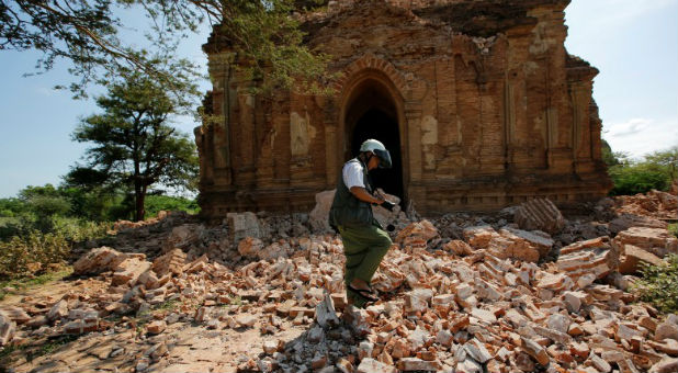 A photograper walks outside a collapsed pagoda after an earthquake in Bagan, Myanmar