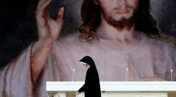 A nun walks past a poster on the main stage before the opening ceremony of World Youth Day