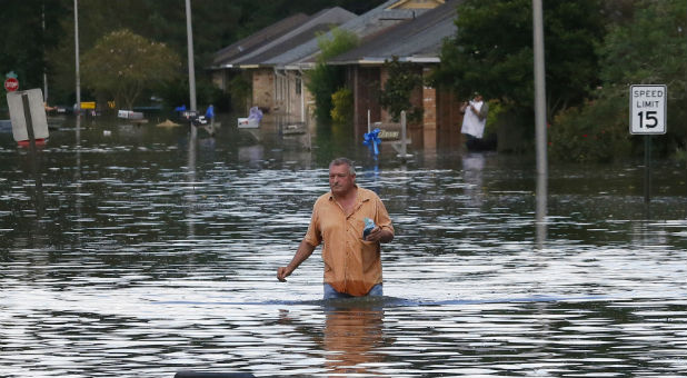 A man wades through a flooded street in Ascension Parish, Louisiana