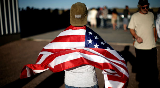 A man drapes an American flag over his shoulders at a campaign rally for Republican presidential nominee Donald Trump in Colorado Springs