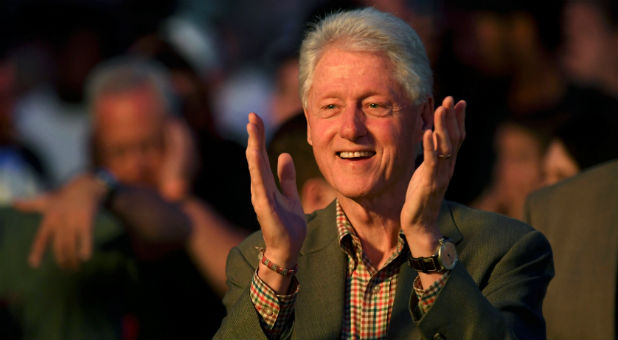Former U.S. president Bill Clinton applauds