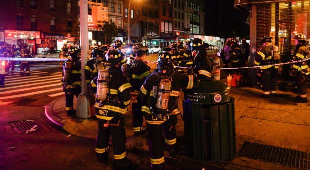 New York City firefighters stand near the site of an explosion in the Chelsea neighborhood of Manhattan, New York