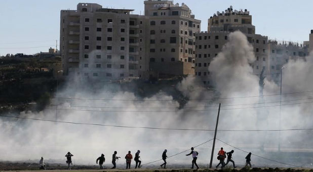 Palestinian protesters run away from tear gas fired by Israeli troops during clashes near the Jewish settlement of Bet El, near the West Bank city of Ramallah
