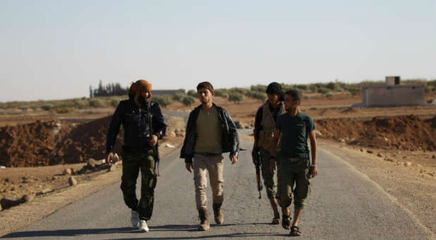 Rebel fighters of 'Al-Sultan Murad' brigade walk along a street on the outskirts of the northern Syrian town of Shawa, which is controlled by Islamic State militants.