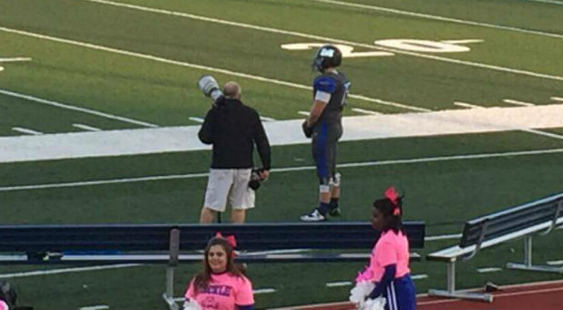 Millikin University football player Connor Brewer stands alone during the national anthem.