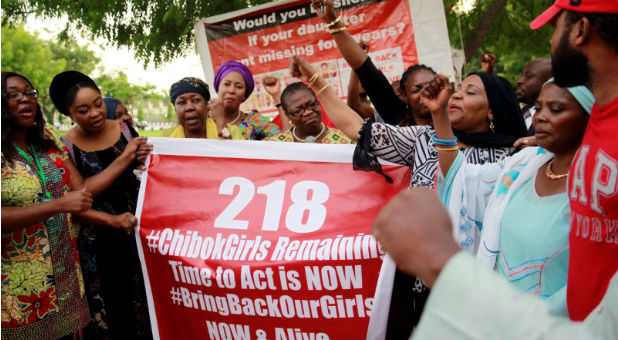 Members of the #BringBackOurGirls (#BBOG) campaign stand behind a banner with Number 218 during a sit-out in Abuja, Nigeria
