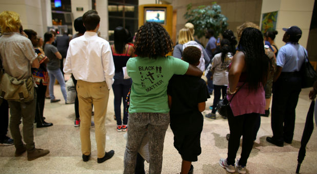 A mother and her children stand among an overflow crowd as they watch and listen outside city council chambers in Charlotte