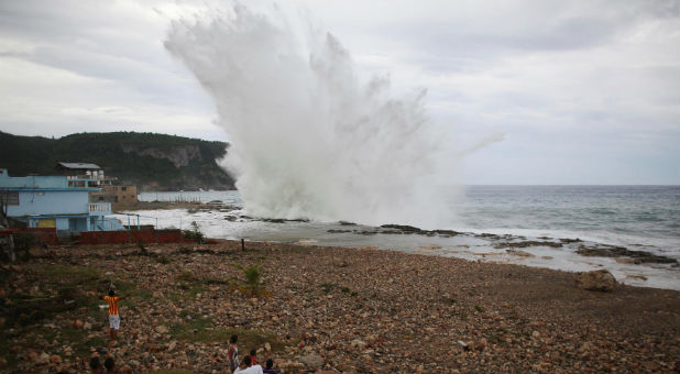 People watch waves splashing on the beach at Siboney ahead of the arrival of Hurricane Matthew in Cuba