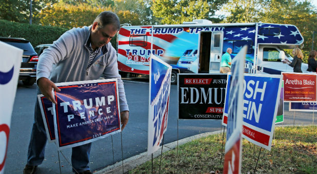 Supporter Chuck McAllister places a Trump-Pence sign outside of the Morrison Library as early voting continues in Charlotte