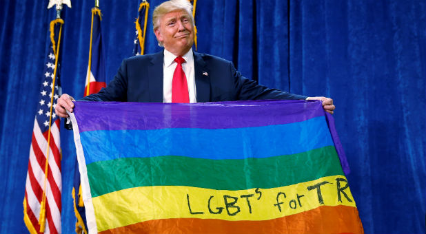 Republican presidential nominee Donald Trump holds up a rainbow flag with