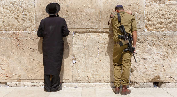 An IDF soldier and an Orthodox Jew pray at the Western Wall.