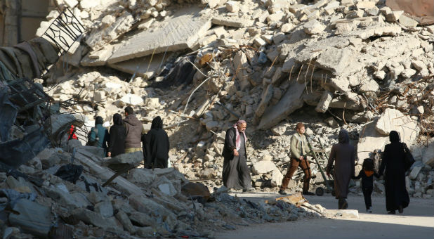 People walk past rubble of damaged buildings in a rebel-held besieged area in Aleppo