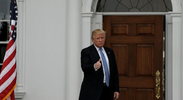 U.S. President-elect Donald Trump gestures from the front door at the main clubhouse at Trump National Golf Club.