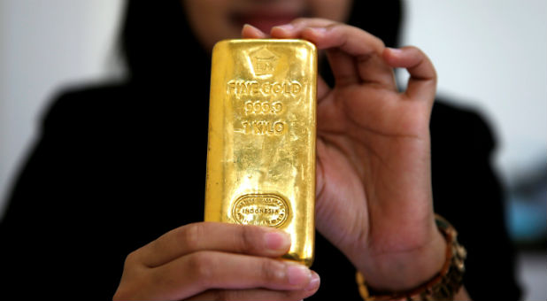An employee of PT Aneka Tambang Tbk poses with a kilogram of gold bar