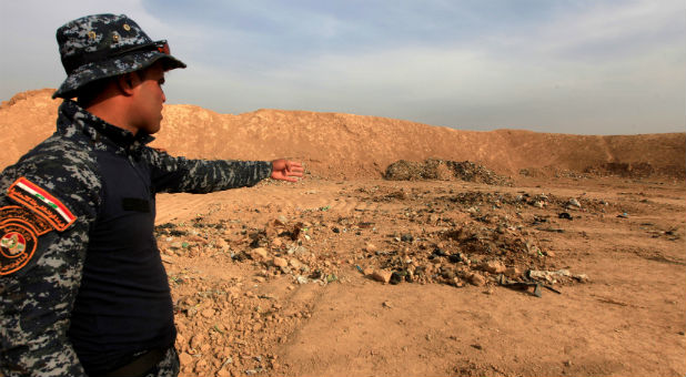 A member of Iraqi security forces gestures towards a mass grave in the town of Hammam al-Alil, which was seized from Islamic State last week.