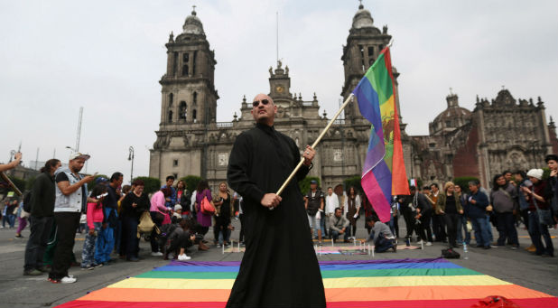 An activist holds a rainbow flag during a protest by the LGBT community against violence against transgenders outside Metropolitan Cathedral in Mexico City, Mexico