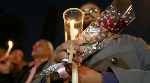 Egyptians hold candles and a cross in front of the Coptic Christian Cathedral in tribute to the victims of the bomb attack following a deadly explosion inside a Coptic cathedral in Cairo