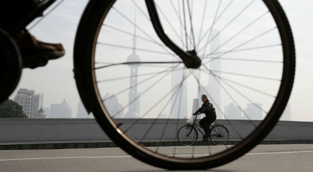 People ride bicycles on a bridge in front of the financial district of Pudong amid heavy smog in Shanghai, China