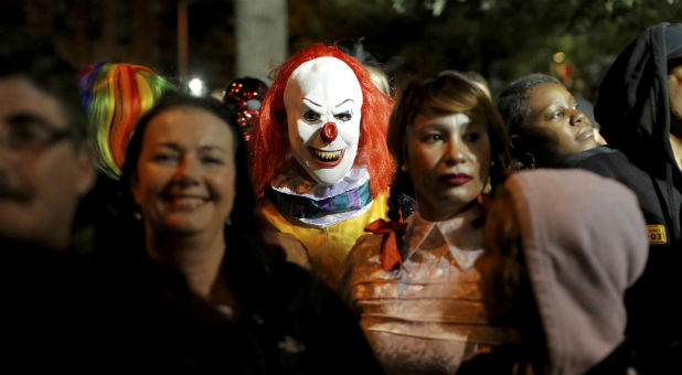 A person dressed in a clown costume stands among attendees during the Greenwich Village Halloween Parade in Manhattan.