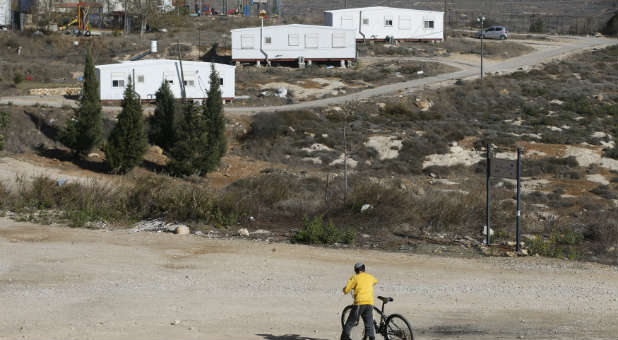 An Israeli boy holds his bicycle near homes in the Jewish settler outpost of Amona in the West Bank.