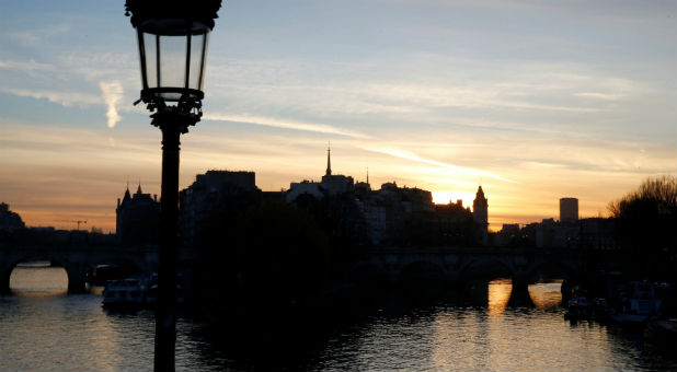 The sun rises above the Seine River skyline in central Paris