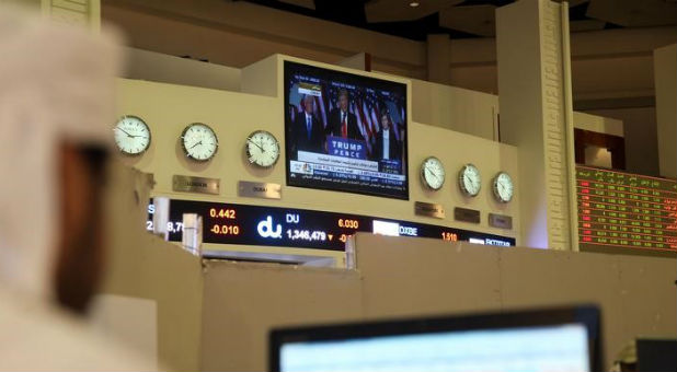 A screen showing U.S. President-elect Donald Trump is seen as a trader monitors stock information at Dubai Financial Market, in Dubai, United Arab Emirates