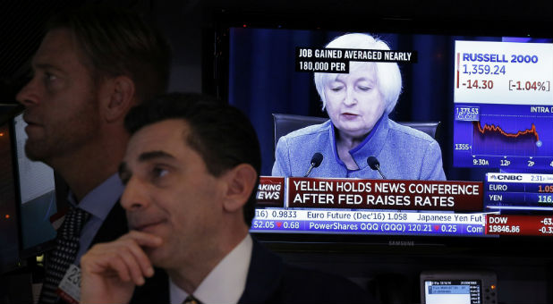 Traders works on the floor of the New York Stock Exchange (NYSE) as a television screen displays coverage of U.S. Federal Reserve Chairman Janet Yellen shortly after the announcement that the U.S. Federal Reserve will hike interest rates