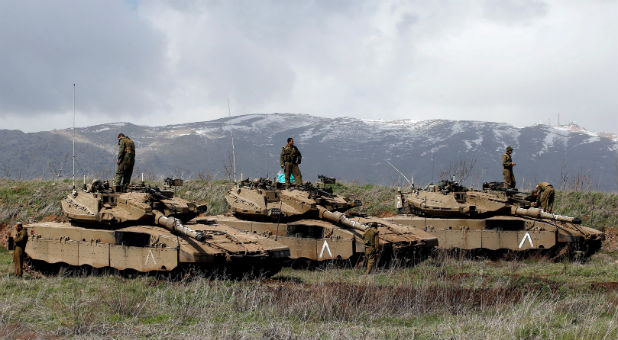 Israeli soldiers stand atop tanks in the Golan Heights near Israel's border with Syria