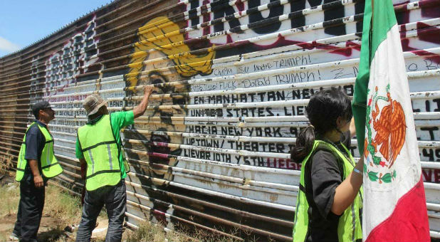 After being deported, Mexican nationals spray-paint part of the border fence near Tijuana, Mexico, that includes a likeness of Donald Trump, then still a presidential candidate, in this May 10 photo