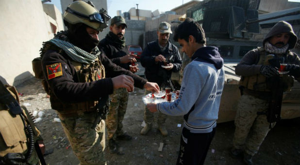 A civilian hands out tea to members of the Iraqi rapid response forces during a battle with the Islamic State militants in the Mithaq district of eastern Mosul