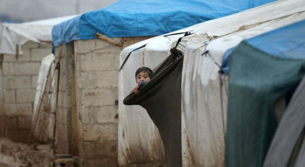 An internally displaced Syrian boy looks out his tent in the Bab Al-Salam refugee camp, near the Syrian-Turkish border