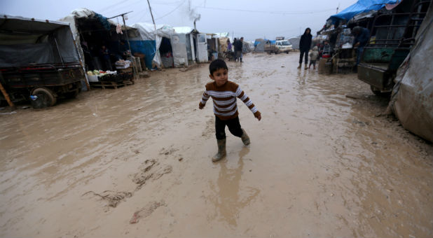 An internally displaced Syrian boy walks over rainwater in the Bab Al-Salam refugee camp, near the Syrian-Turkish border, northern Aleppo province