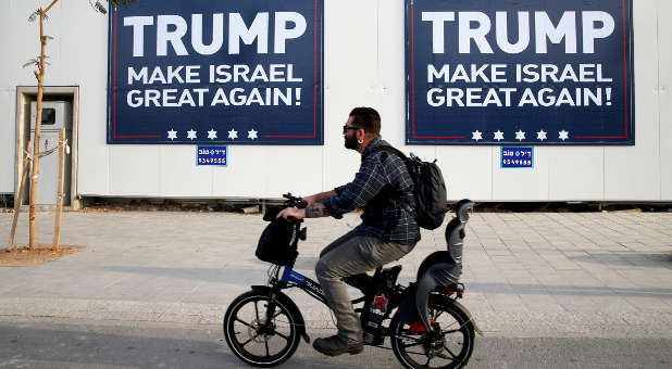 A man cycles past signs bearing the name of U.S. President Donald Trump in Tel Aviv, Israel, Nov. 14, 2016.